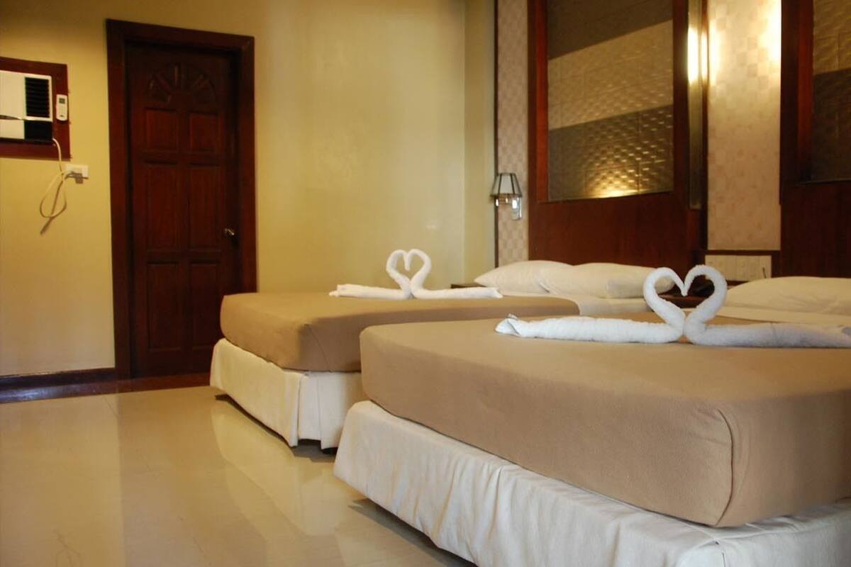 A hotel room with two beds, each with a heart-shaped towel arrangement.