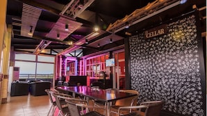 A modern bar area with a large table and chairs, a wall with a pattern, and a sign that reads "CELLAR". - Staylite Hotel (Candon)