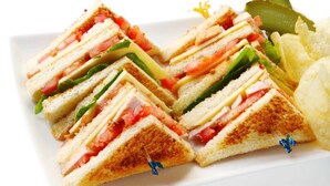 A plate of sandwiches with pickles and chips. - Staylite Hotel (Candon)