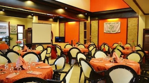 A conference room with multiple tables set for a meeting, a projector screen, and banners on the walls. - Staylite Hotel (Candon)