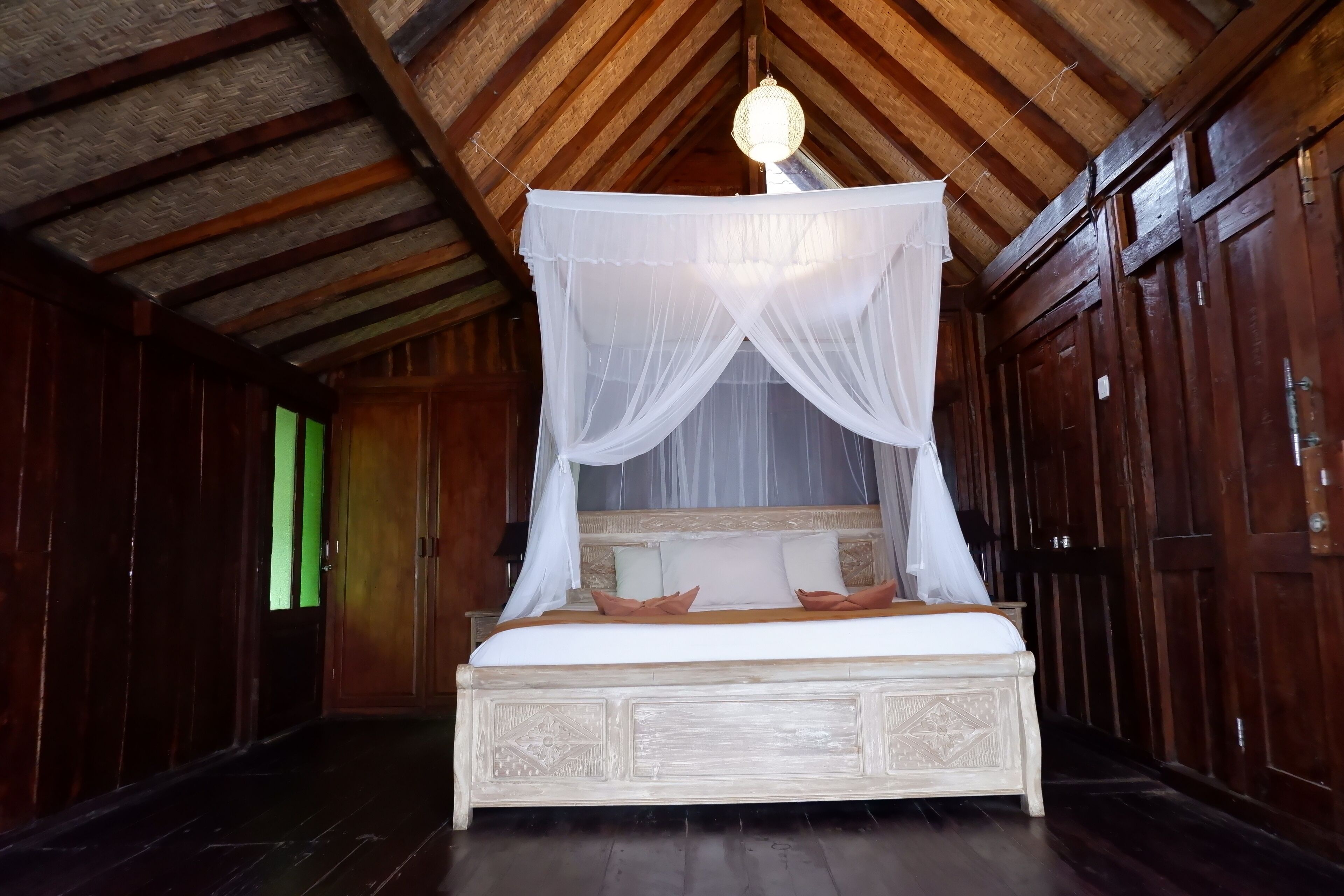 Una habitación de madera con una cama bajo un dosel, paredes de madera y techo inclinado.
