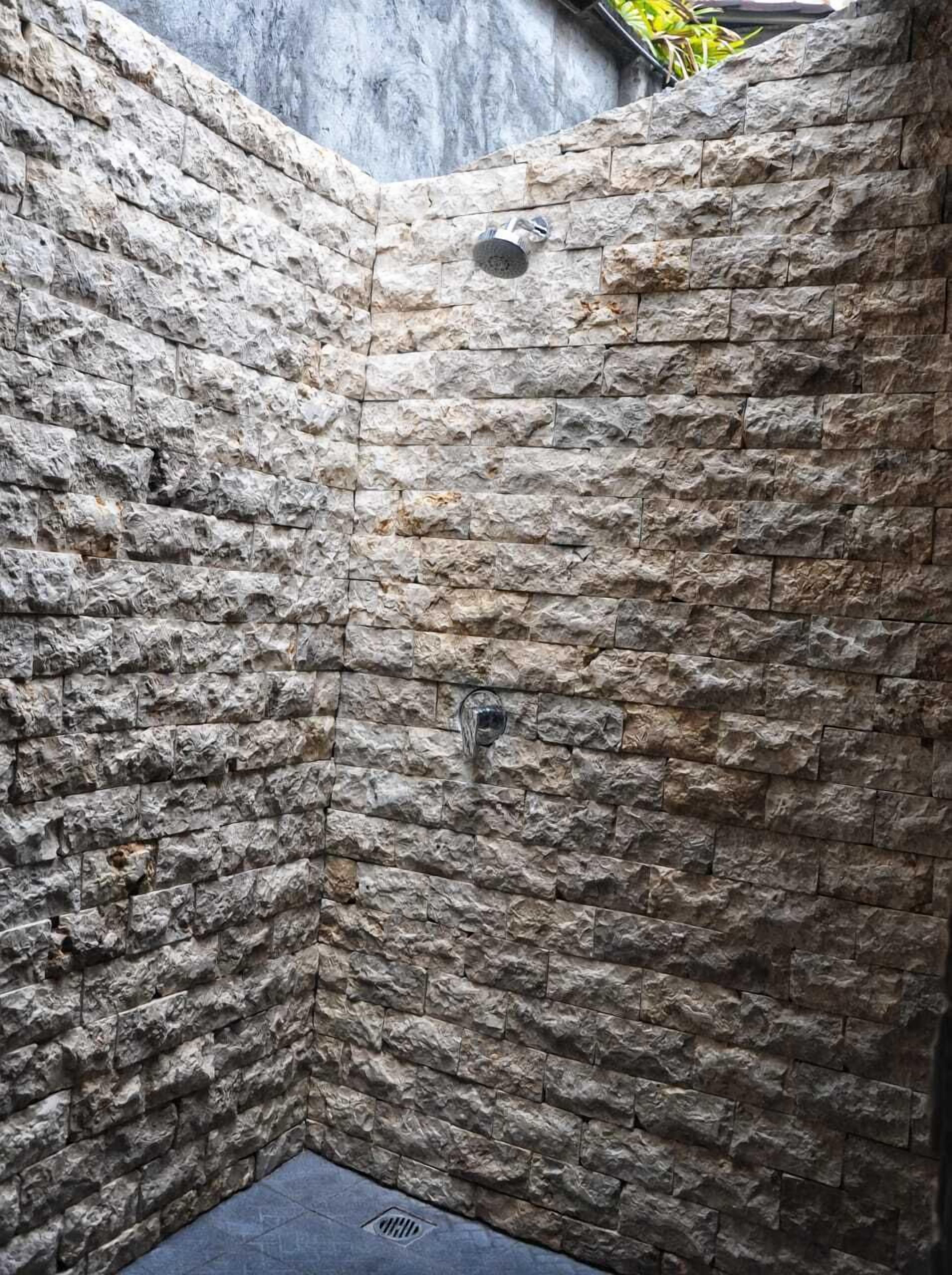 A stone-walled shower area with a built-in showerhead.