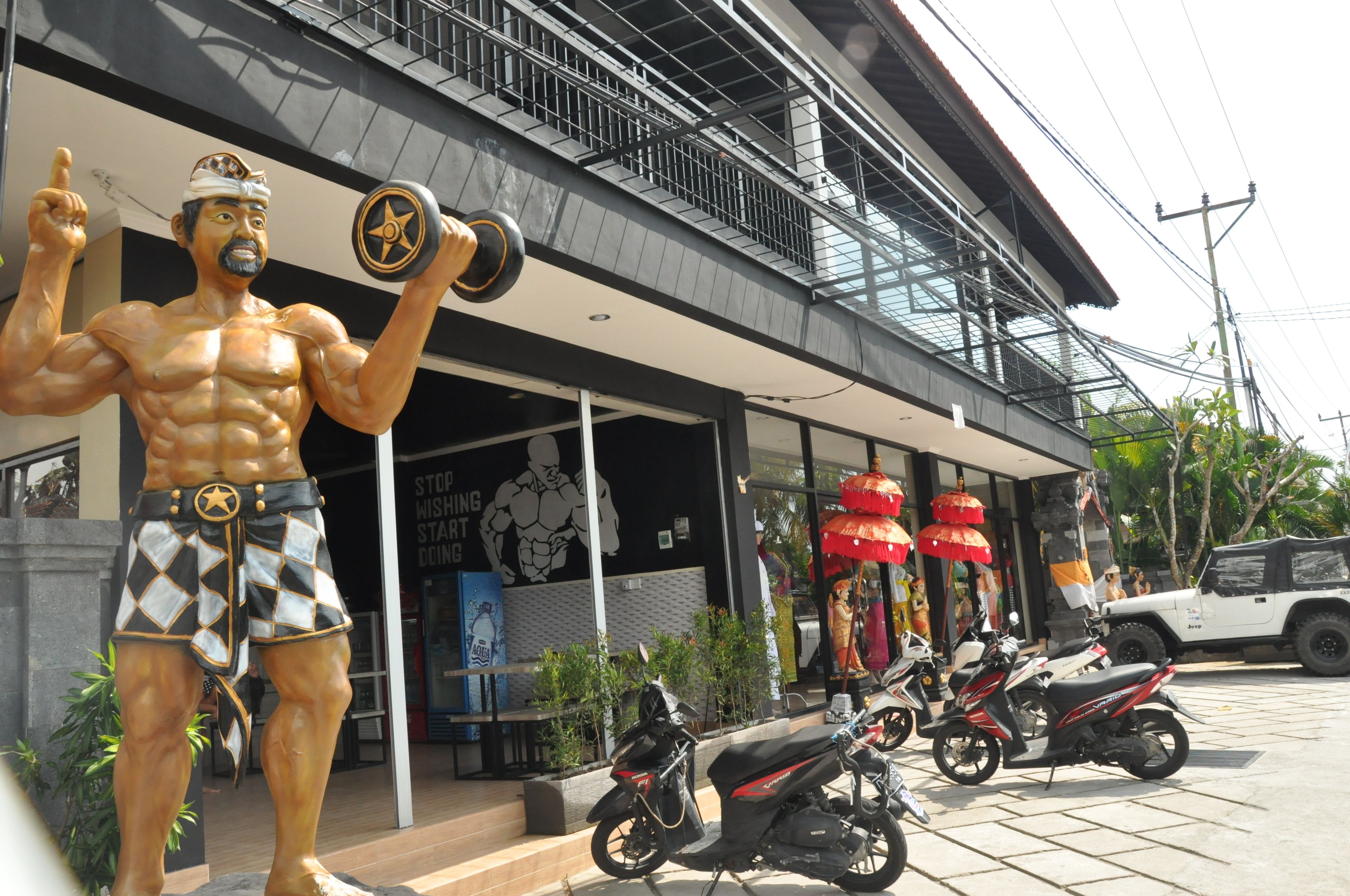 A muscular statue outside a building with a sign that reads "STORYING STUDIO."