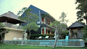 A two-story building with a swimming pool, lounge chairs, and a thatched-roof structure. - Kubudiuma Villas (Pererenan)