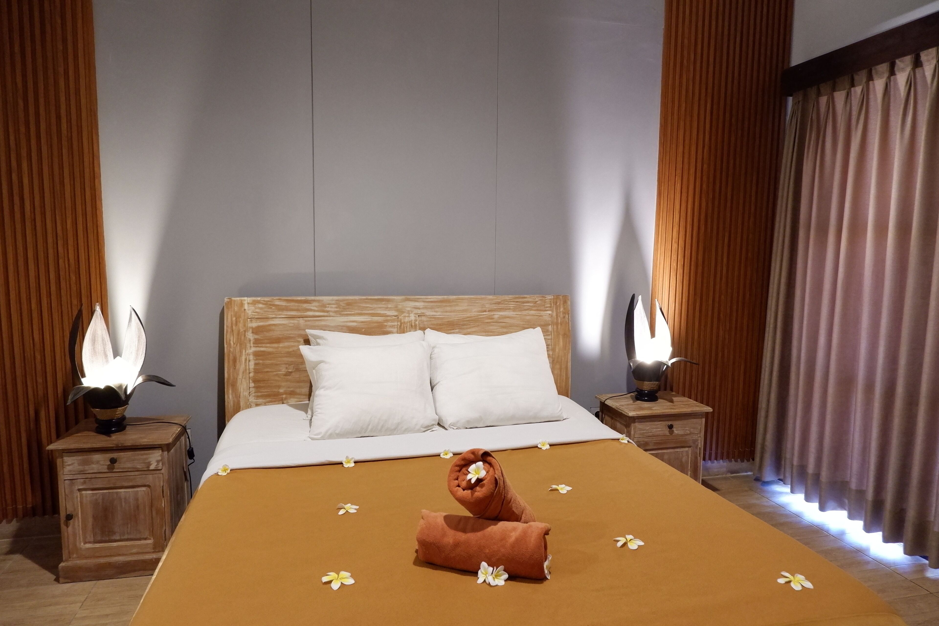 A neatly made bed with white pillows, a brown blanket, and a towel folded at the foot.