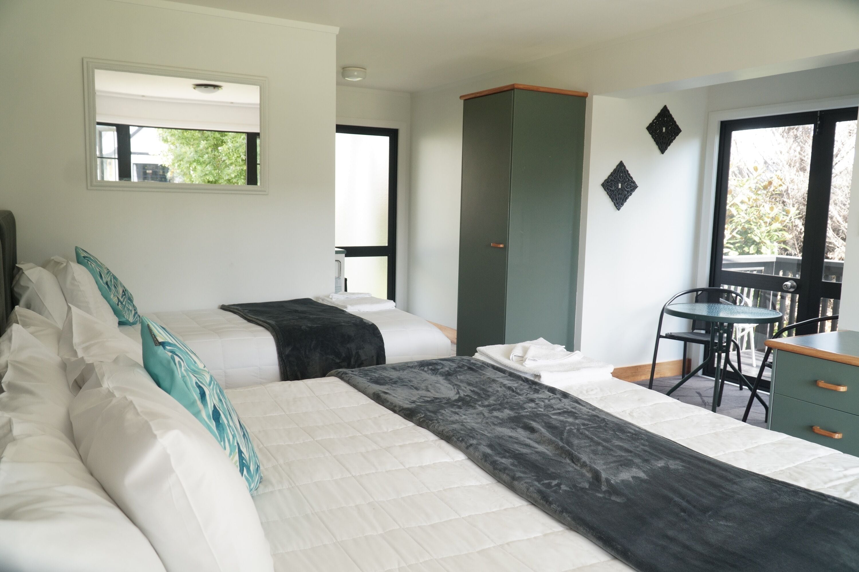 A hotel room with two beds, a desk, a chair, and a wardrobe.