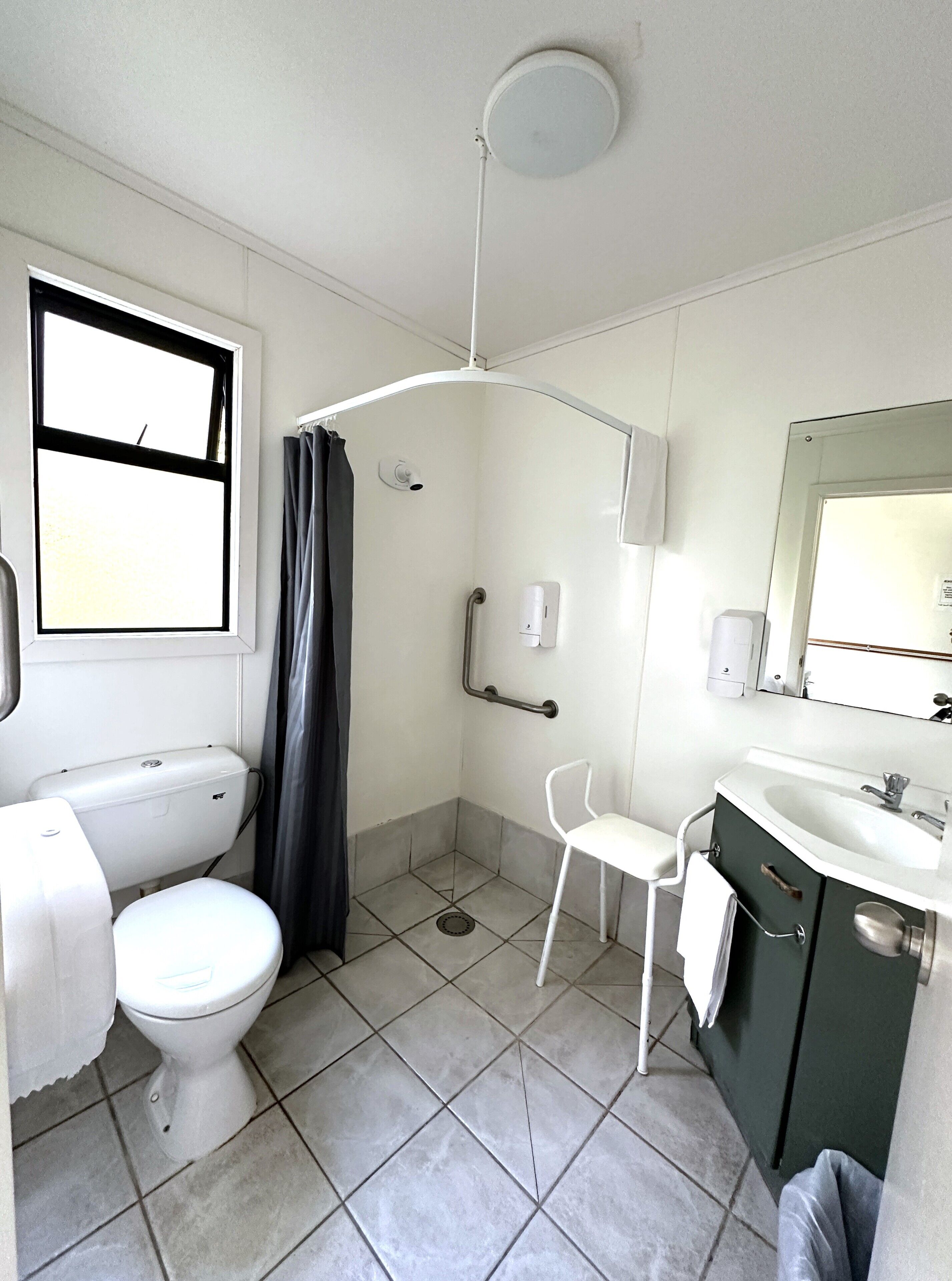 A bathroom with a toilet, a shower, a sink, and a mirror.