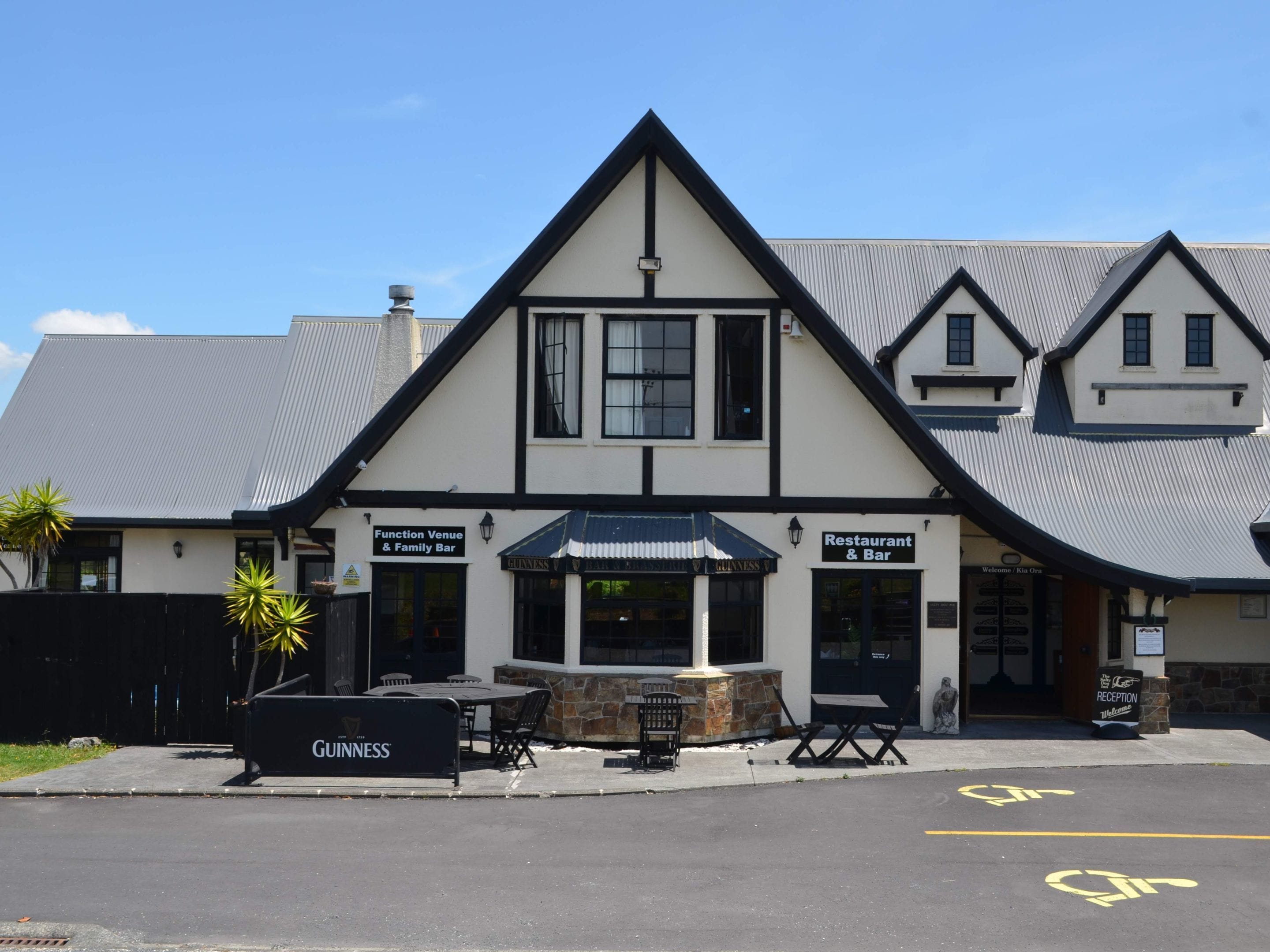 A building with a sign for a function venue and family bar, a reception area, and outdoor seating with tables and chairs.