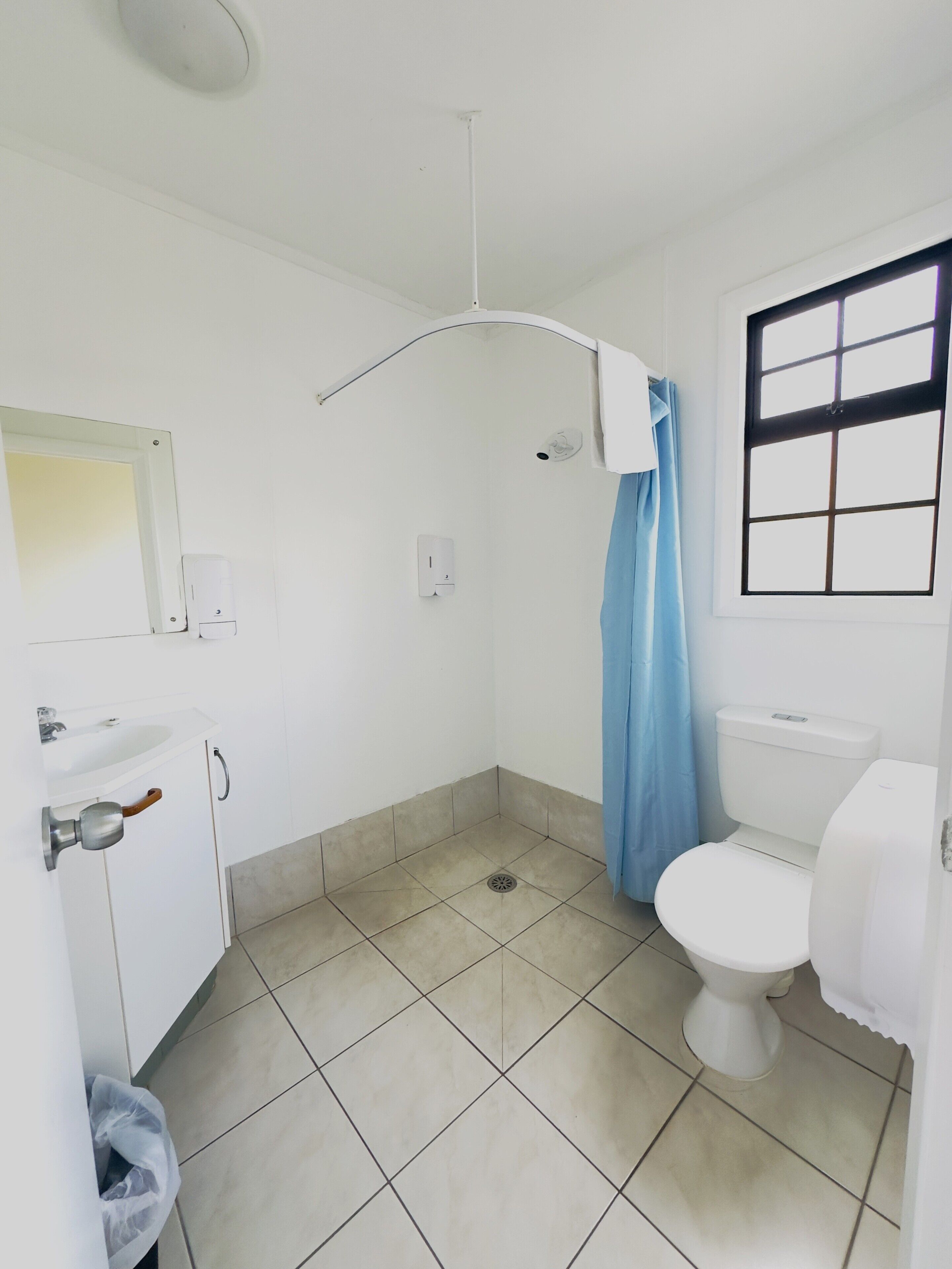 A small, clean bathroom with a toilet, sink, and shower curtain.