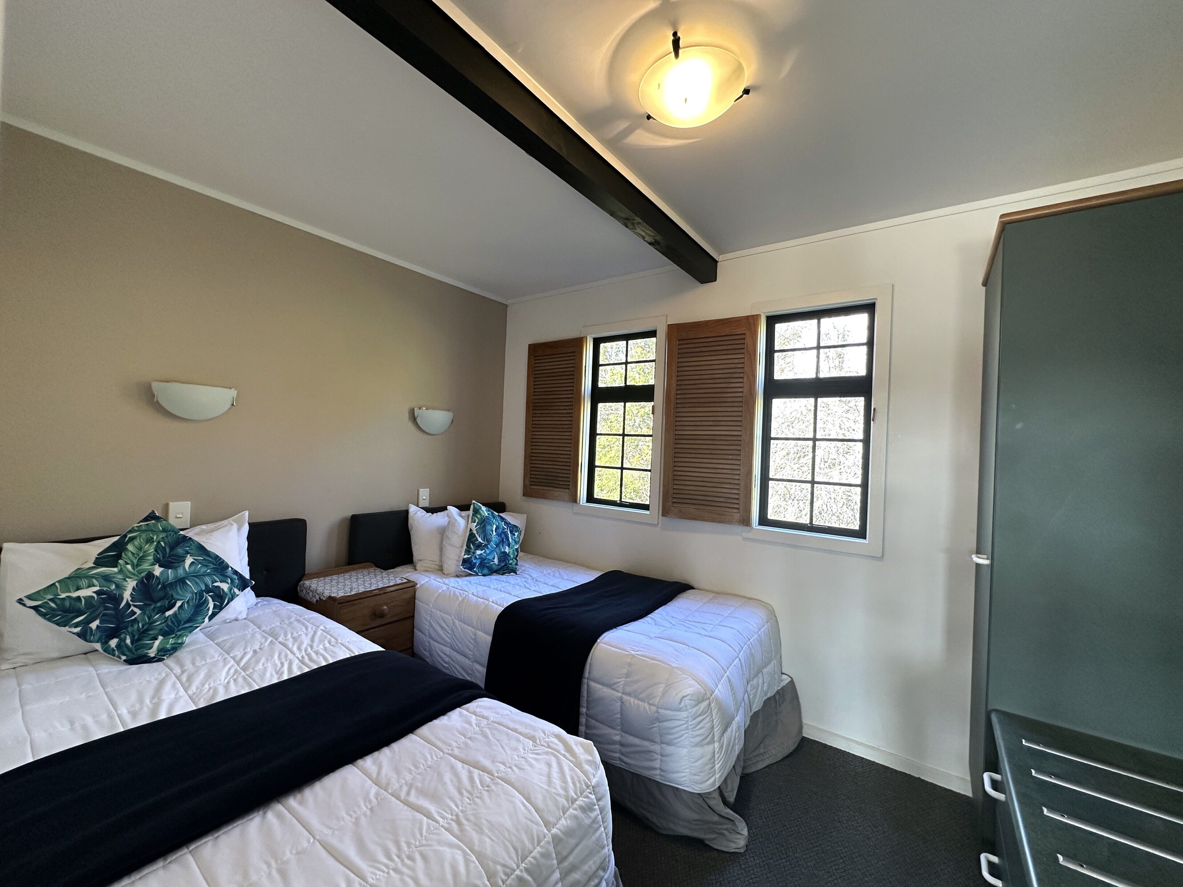 Una habitación con dos camas, un armario y una ventana con contraventanas.