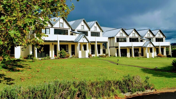 A large, multi-story building with a symmetrical facade, multiple windows, and a covered outdoor area. - Salty Dog Inn (Snells Beach)