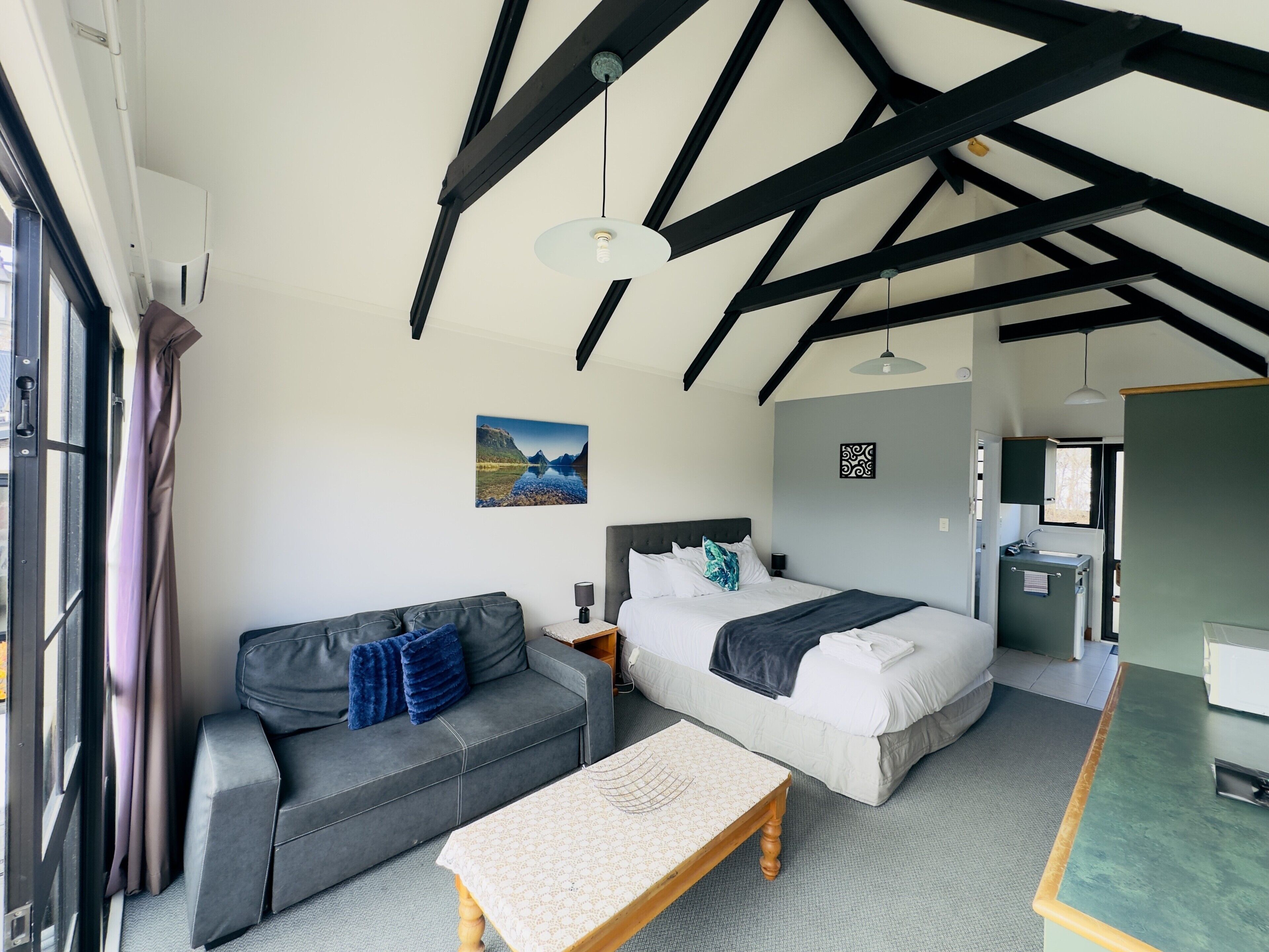A room with a bed, a sofa, a table, and a window.