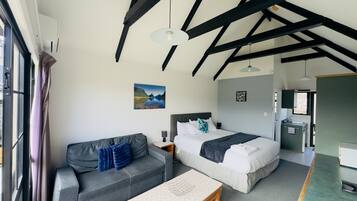 A room with a bed, a sofa, a table, and a window.
