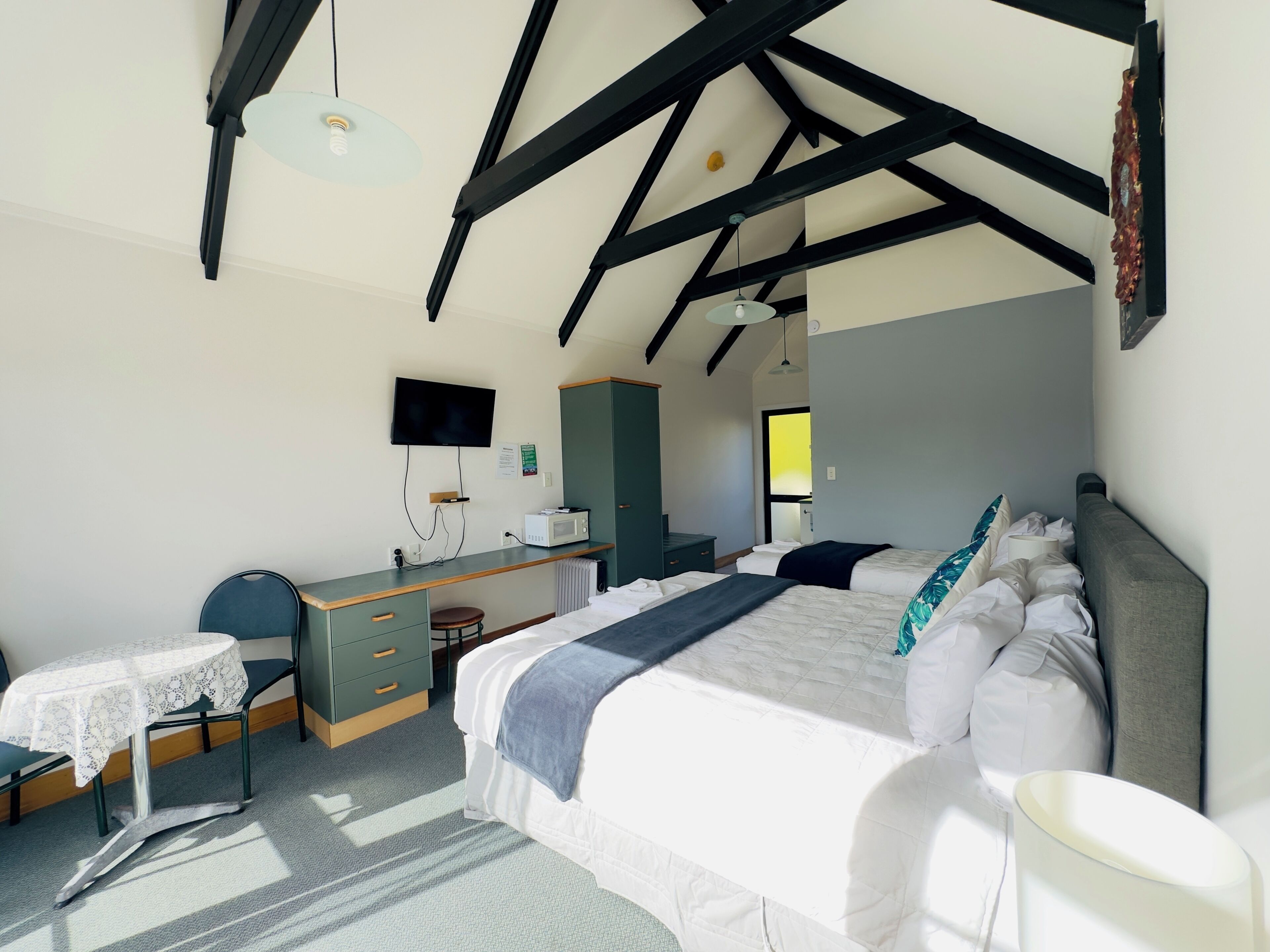 A bedroom with a bed, desk, chair, and a television on the wall.