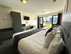 Habitación de hotel con cama, escritorio, silla, televisión y vista al exterior.