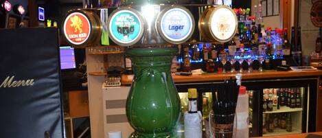 A bar with a green beer tap display and a menu stand.