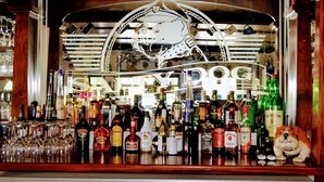 A bar with a variety of liquor bottles and glasses. - Salty Dog Inn (Snells Beach)
