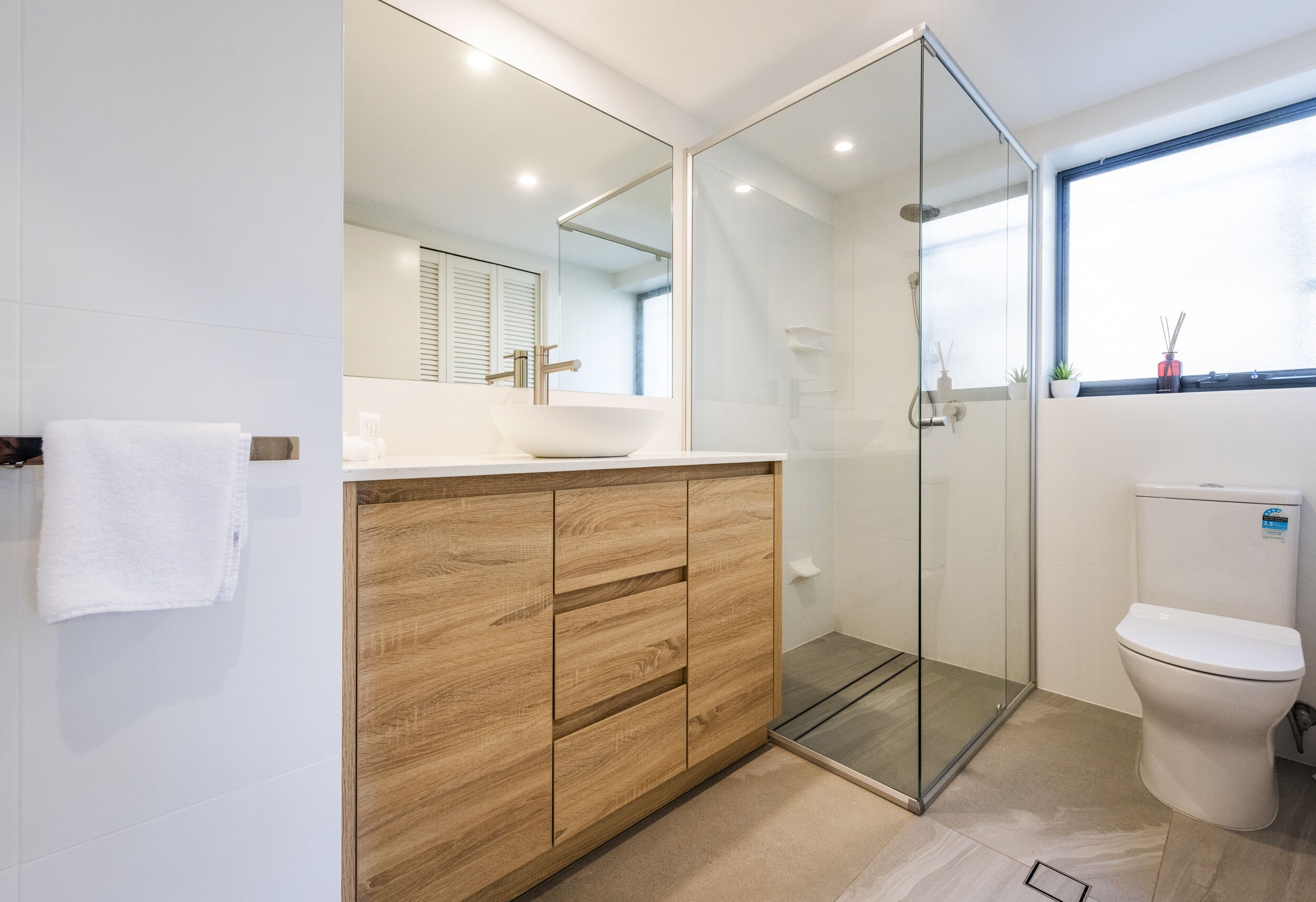 Ein modernes Badezimmer mit Duschkabine aus Glas, einem weißen Waschbecken und einer Toilette.