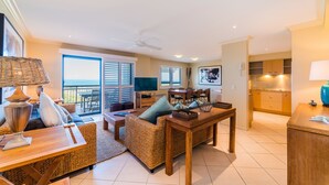 Amplia sala de estar con mesa de comedor, muebles de mimbre y vista al mar a través de amplios ventanales.