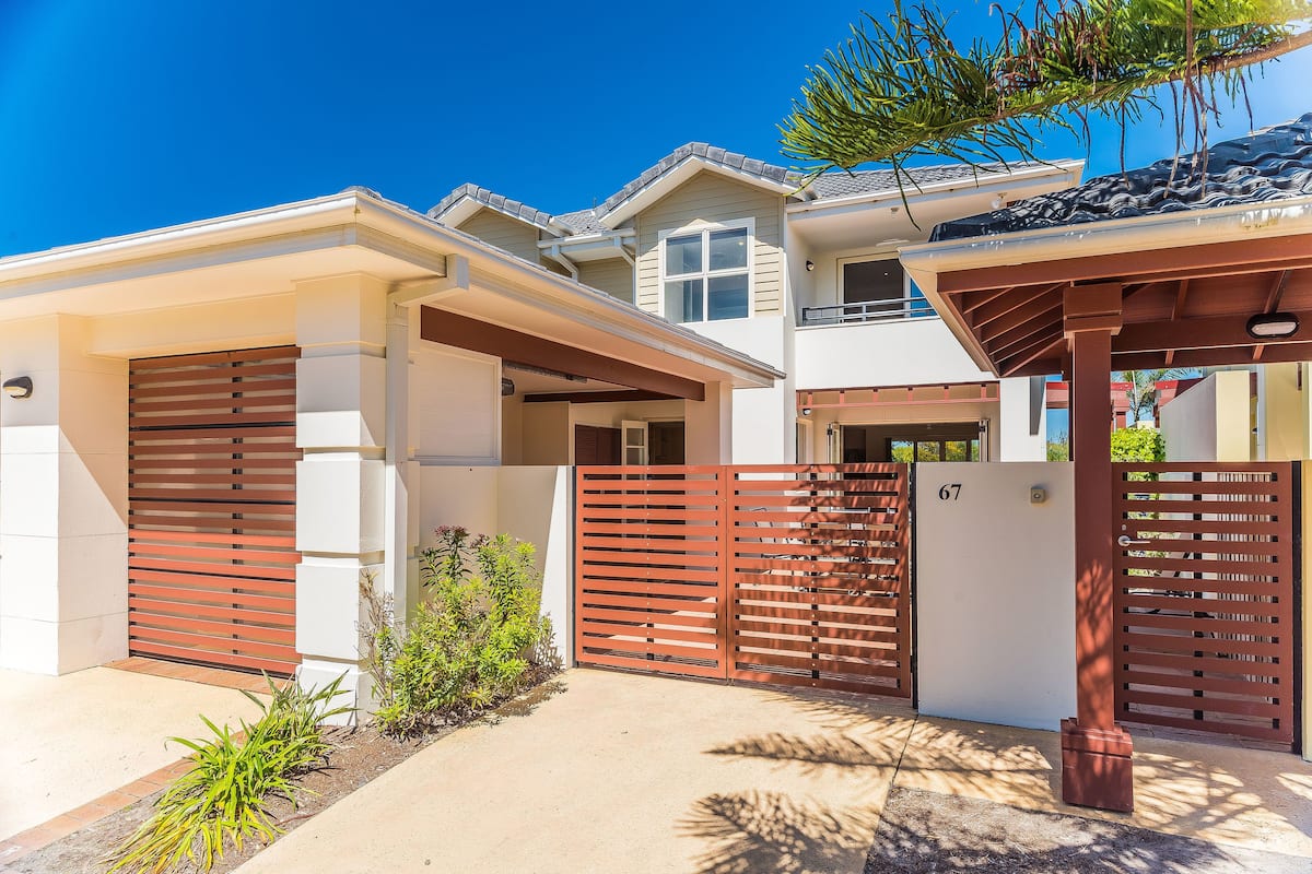 A two-story house with a covered driveway and a gated entrance.