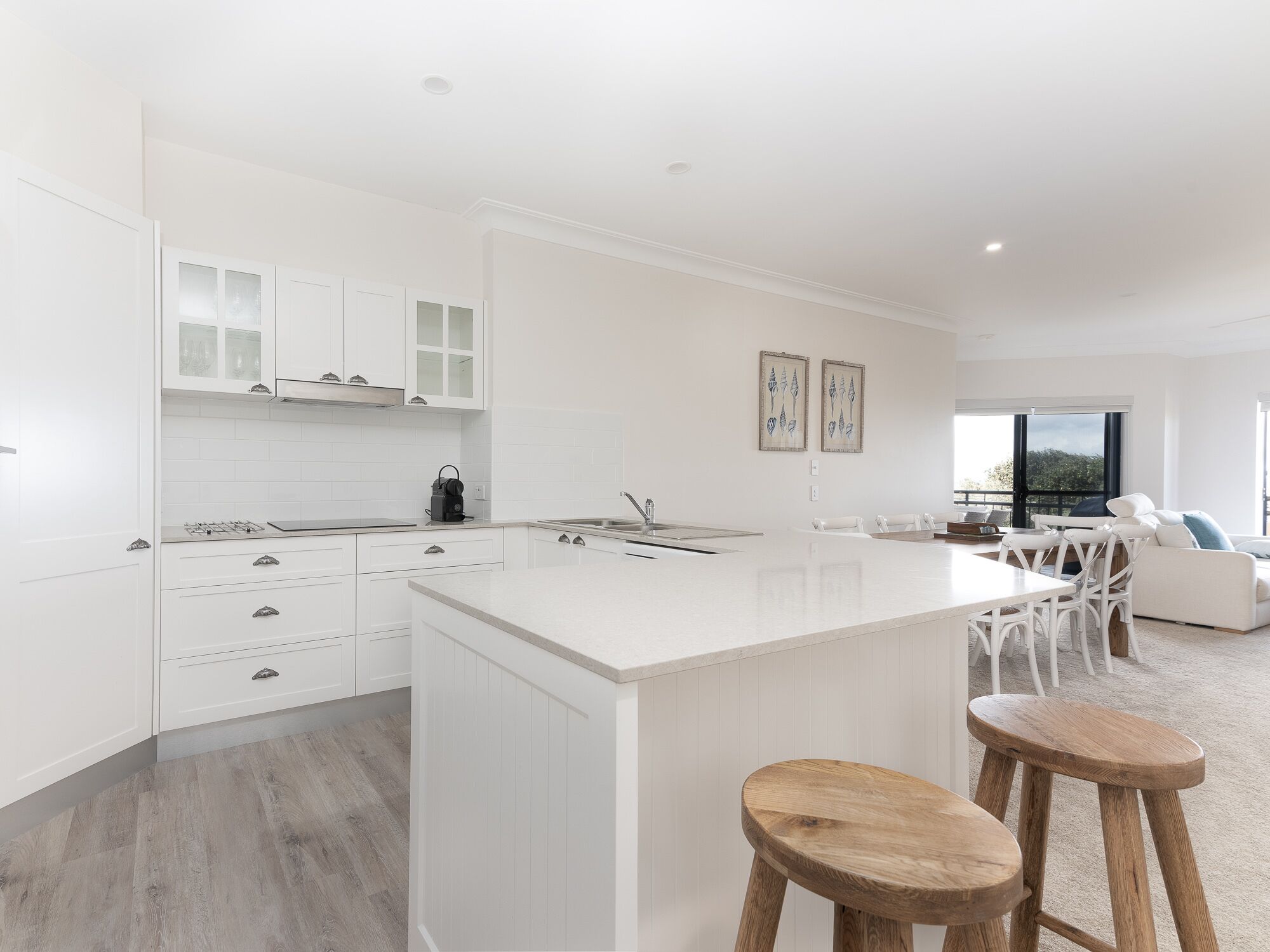 Una cocina moderna con armarios blancos, una isla grande y taburetes de madera.