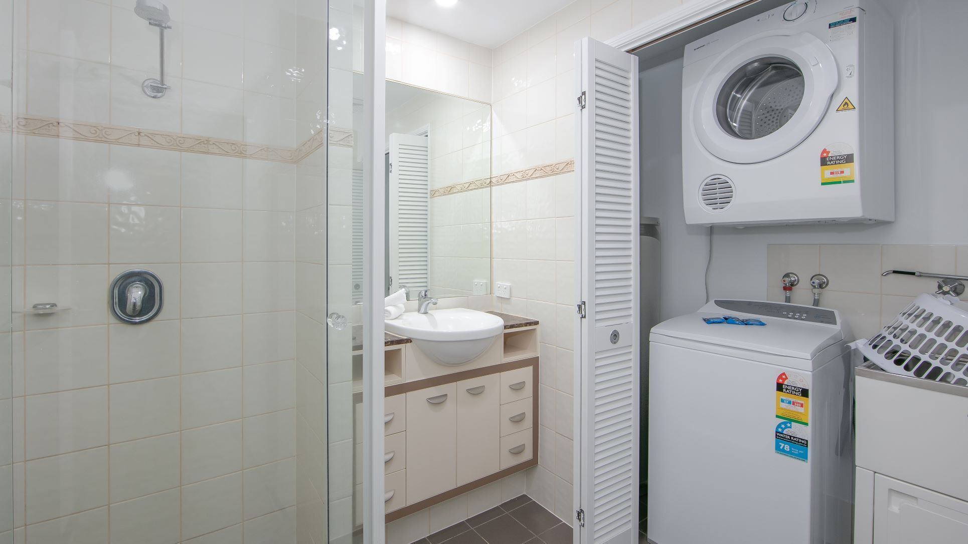 A modern bathroom with a glass shower enclosure, a sink with a vanity, and a built-in washing machine.