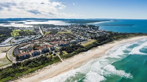 Vista aérea de una zona residencial costera con propiedades frente a la playa, carreteras y un puerto deportivo.
