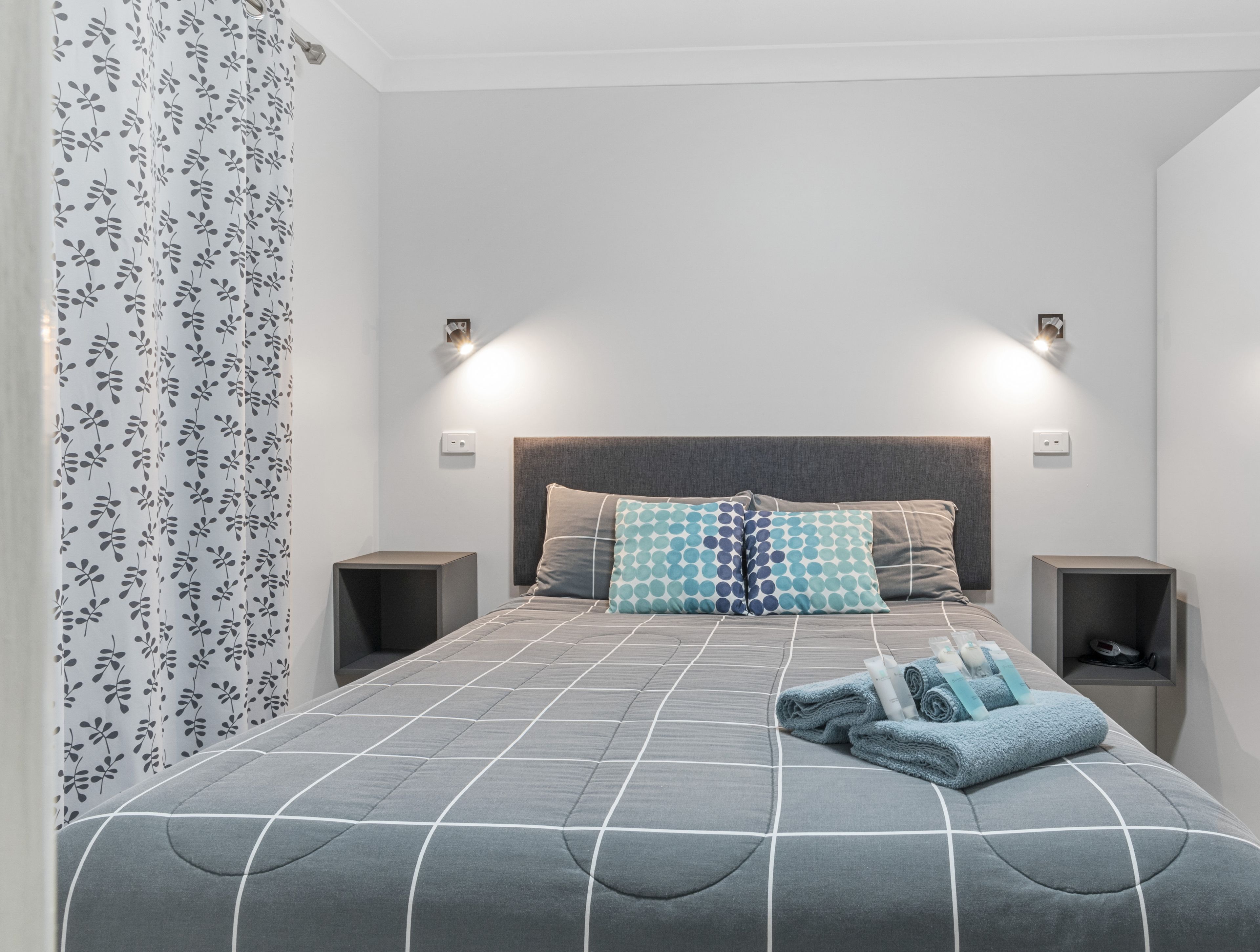 Una camera da letto con un letto, due comodini, una testata e una tenda a motivi floreali.