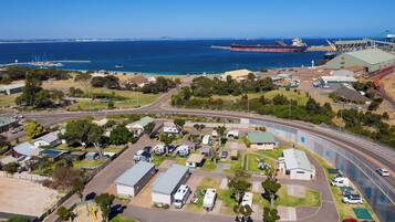 Vue aérienne d’une zone côtière comprenant un port de plaisance, un grand navire de transport de marchandises et une voie ferrée.