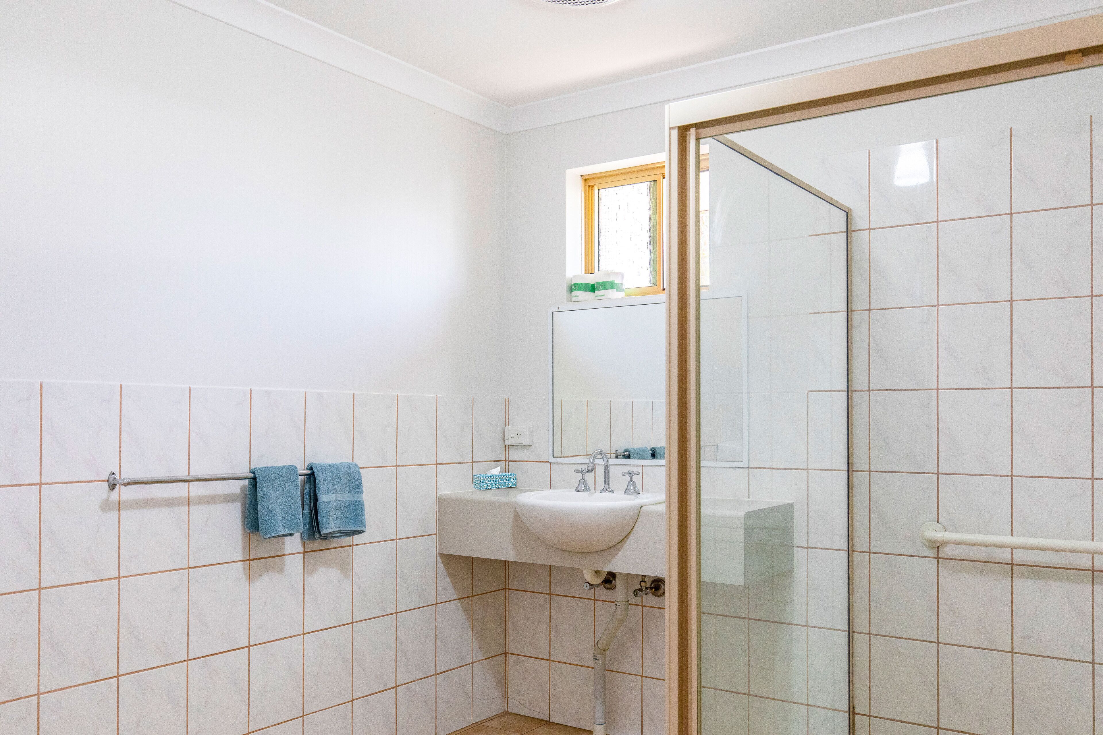 A bathroom with a white sink, a mirror, and a glass shower enclosure.