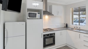 Una cocina moderna con armarios blancos, un microondas, una estufa y un refrigerador.