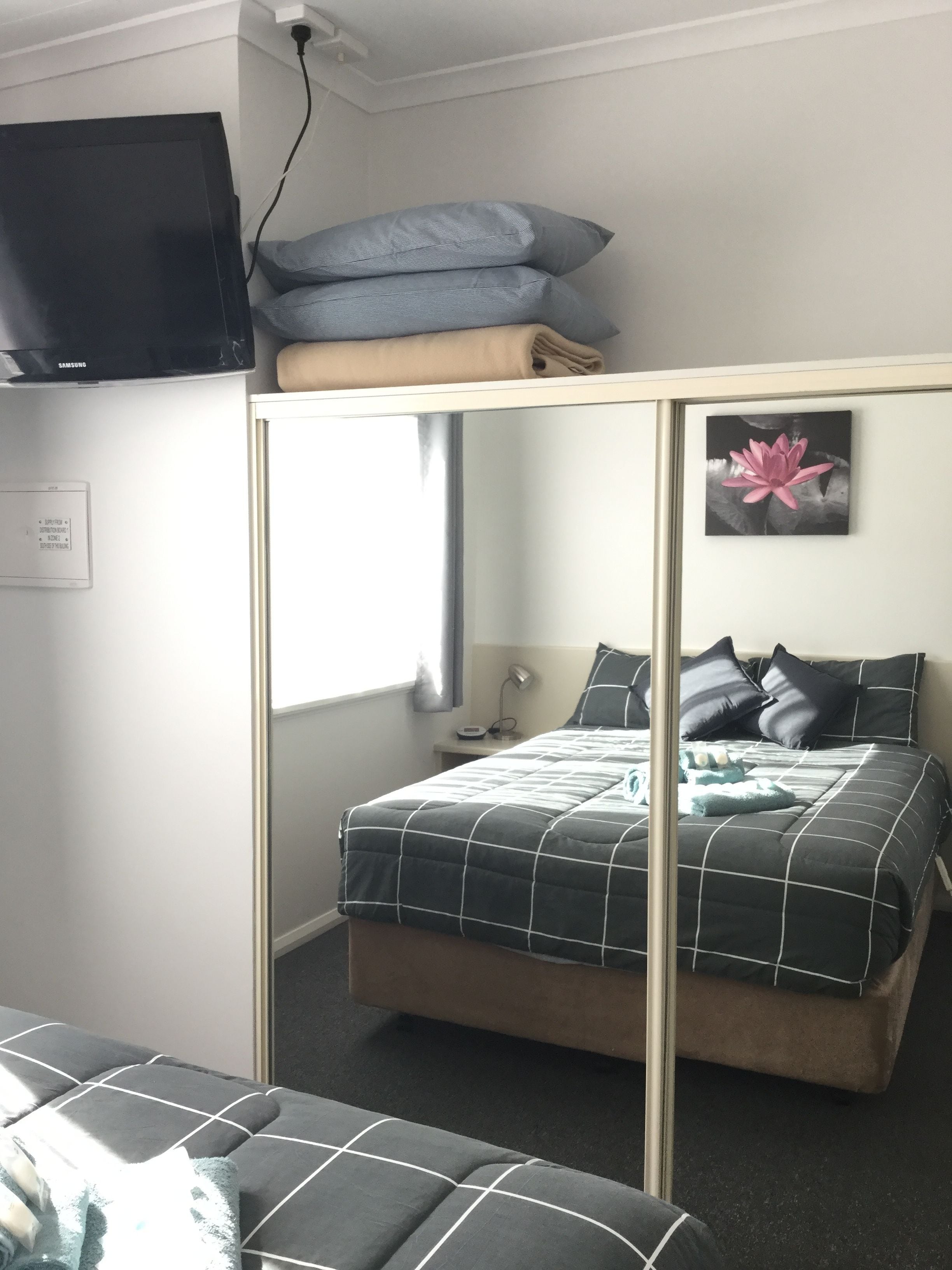 Et lille soveværelse med køjeseng, fladskærms-tv, sengebordlampe og et billede i ramme på væggen.