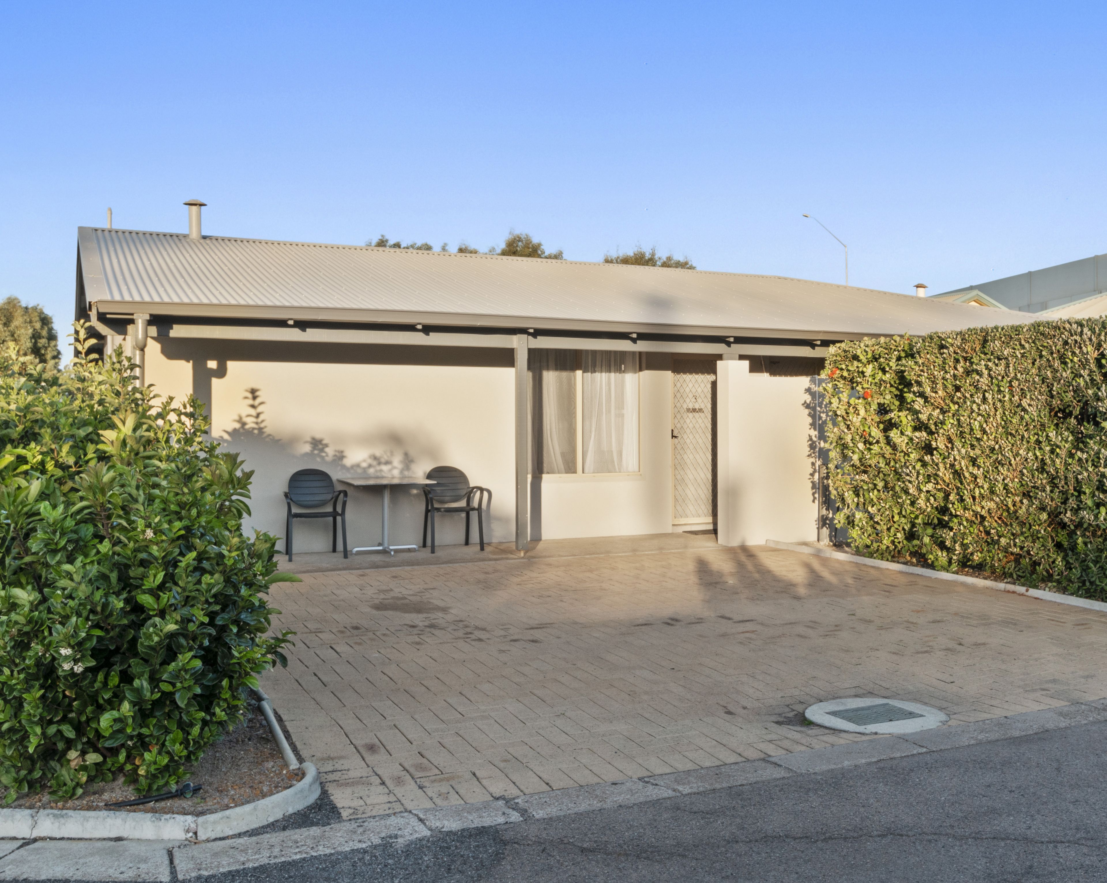 A modern building with a flat roof, a covered entrance, and a paved driveway.