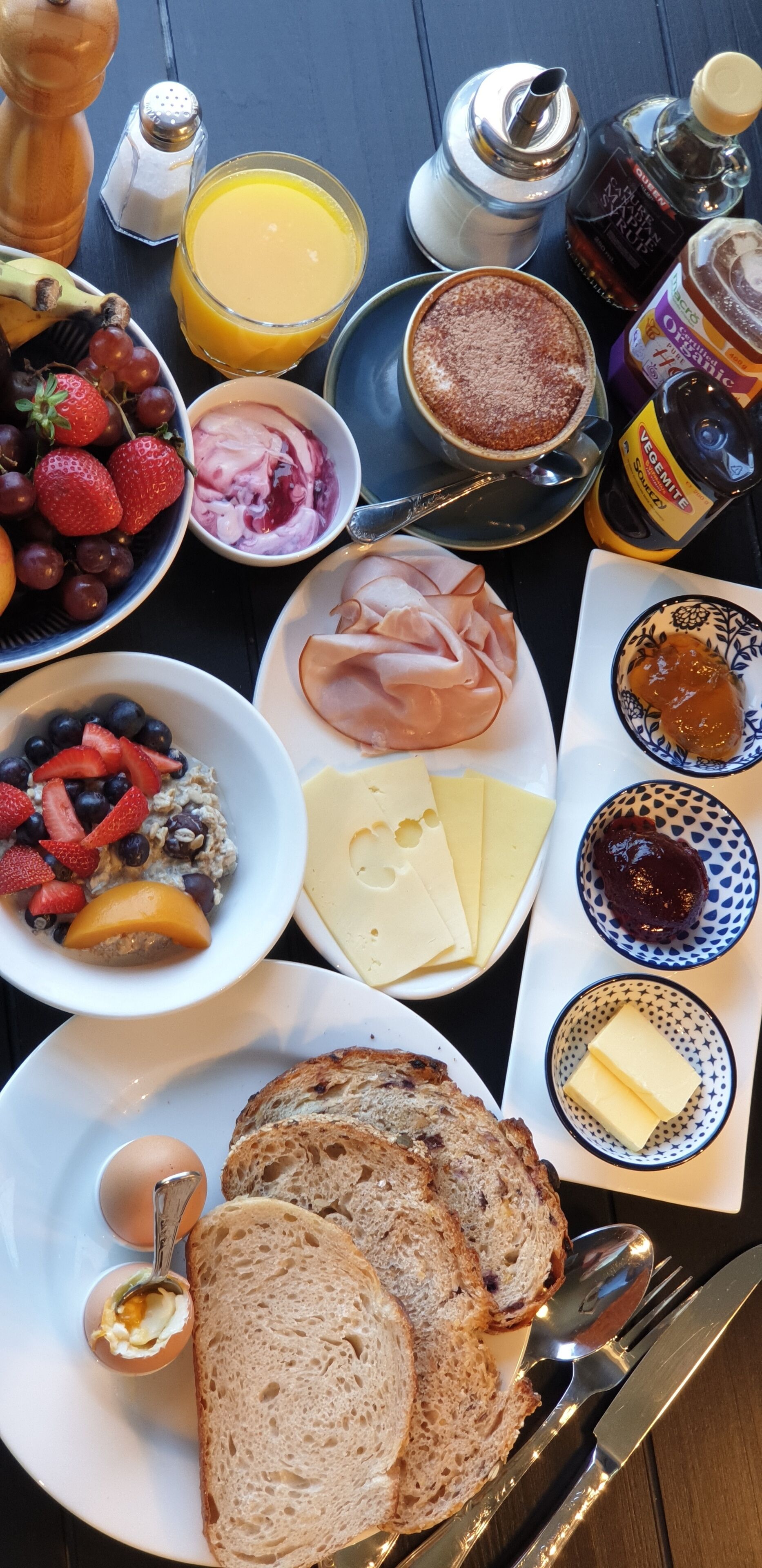 Una mesa de desayuno con diversos alimentos, como pan, huevos, queso y frutas.