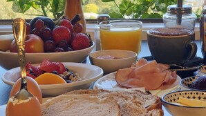 A breakfast table with various food items and a scenic view of a lake and mountains. - Troldhaugen Lodge - Adults Only (Jindabyne)