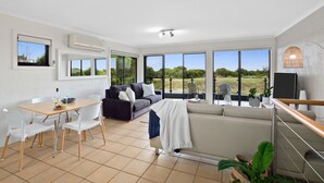 Amplia sala de estar con mesa de comedor, sofá y grandes ventanales con vistas a la vegetación.