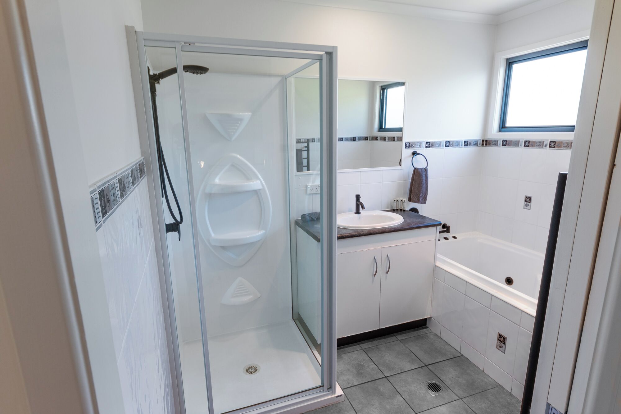 Un baño moderno con ducha de vidrio, lavamanos con encimera y bañera.