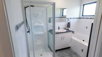 A modern bathroom with a glass-enclosed shower, a sink with a countertop, and a bathtub.