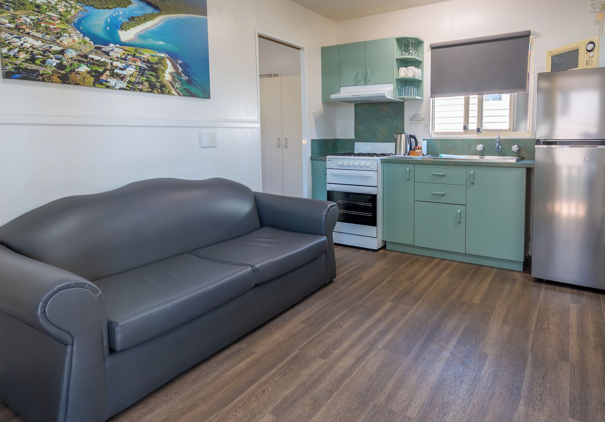 Una cocina compacta con un sofá gris, estufa y refrigerador.