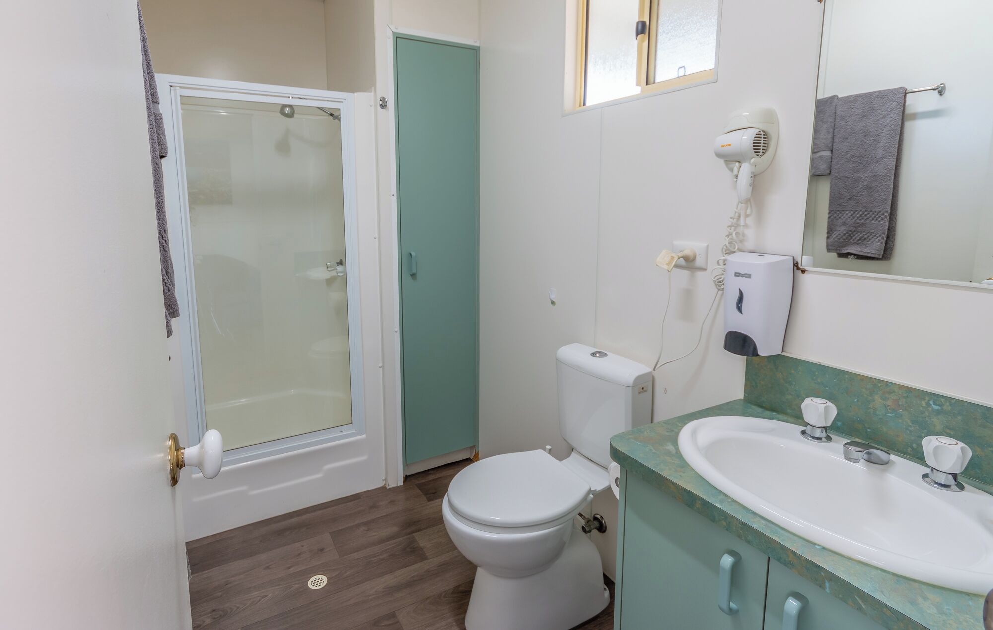 A bathroom with a toilet, a sink, a shower, and a hairdryer.
