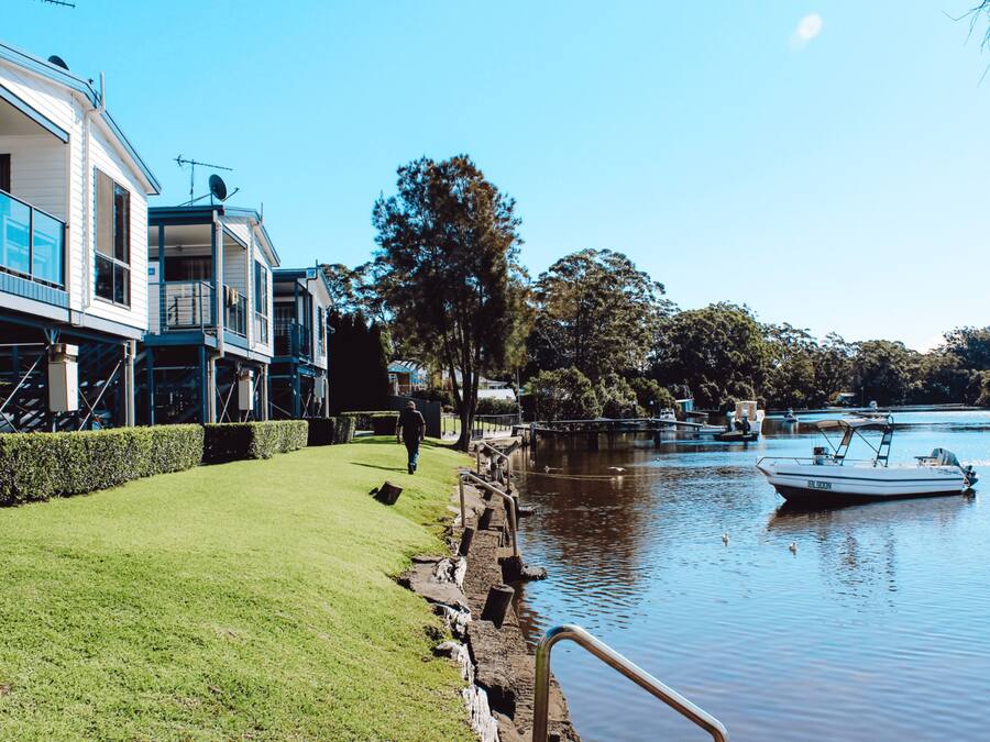 A riverside property with a grassy lawn, a wooden dock, and a boat.