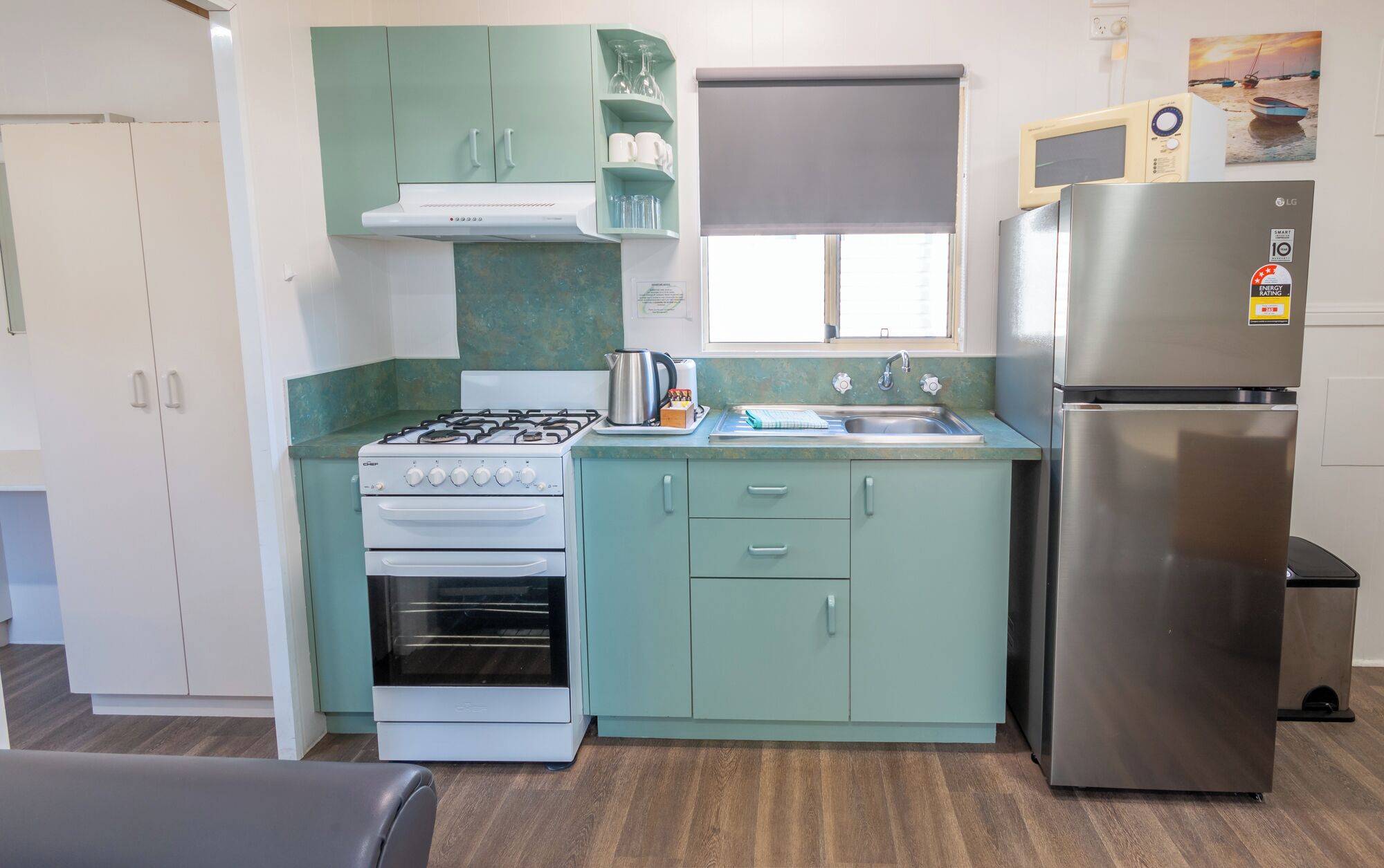 A compact kitchen with a gas stove, oven, sink, and stainless steel refrigerator.