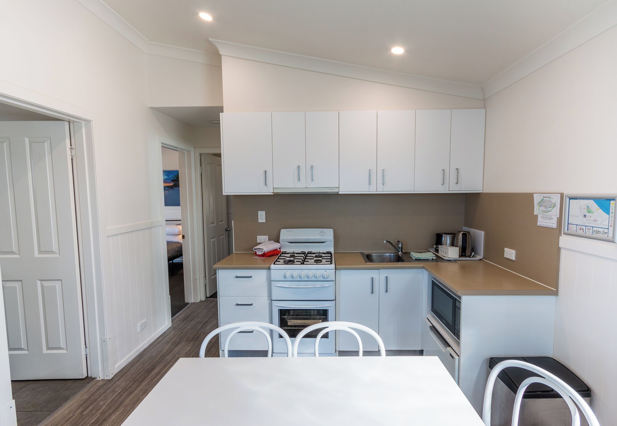 A compact kitchen with white cabinets, a stove, oven, microwave, and a small countertop.