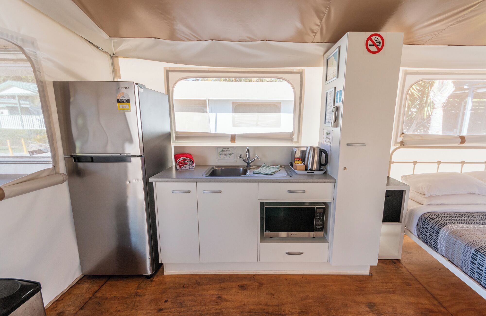 A compact kitchenette with a stainless steel refrigerator, a sink, and a microwave.