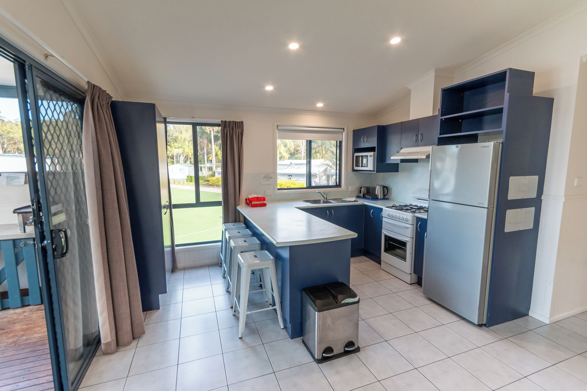 A modern kitchen with a central island, built-in appliances, and a view to the outside.