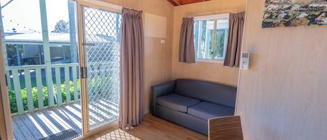 Habitació acollidora amb una porta corredissa de vidre que dona a un balcó, un sofà gris i una taula petita.