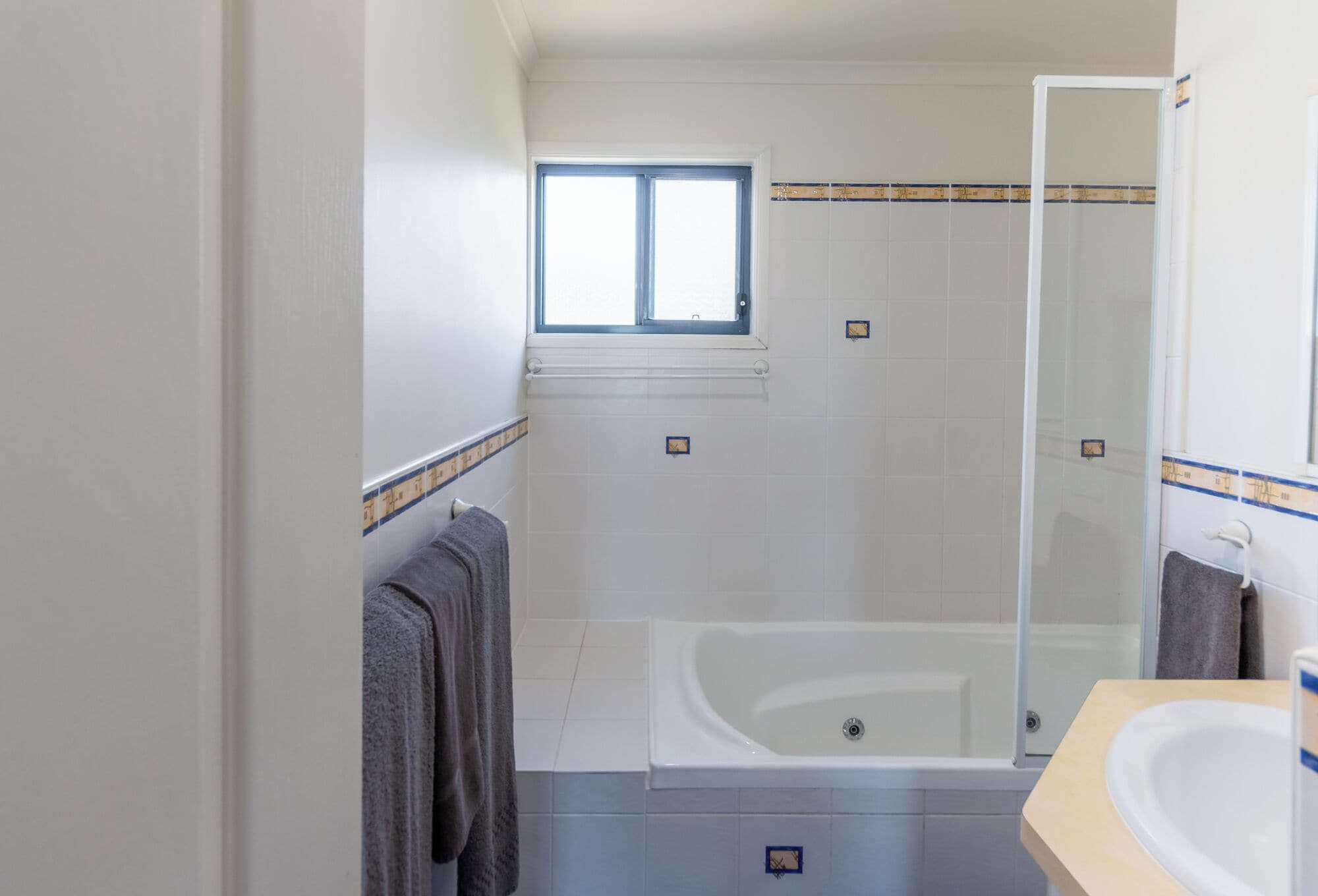 A bathroom with a bathtub, a shower, a sink, and a window.