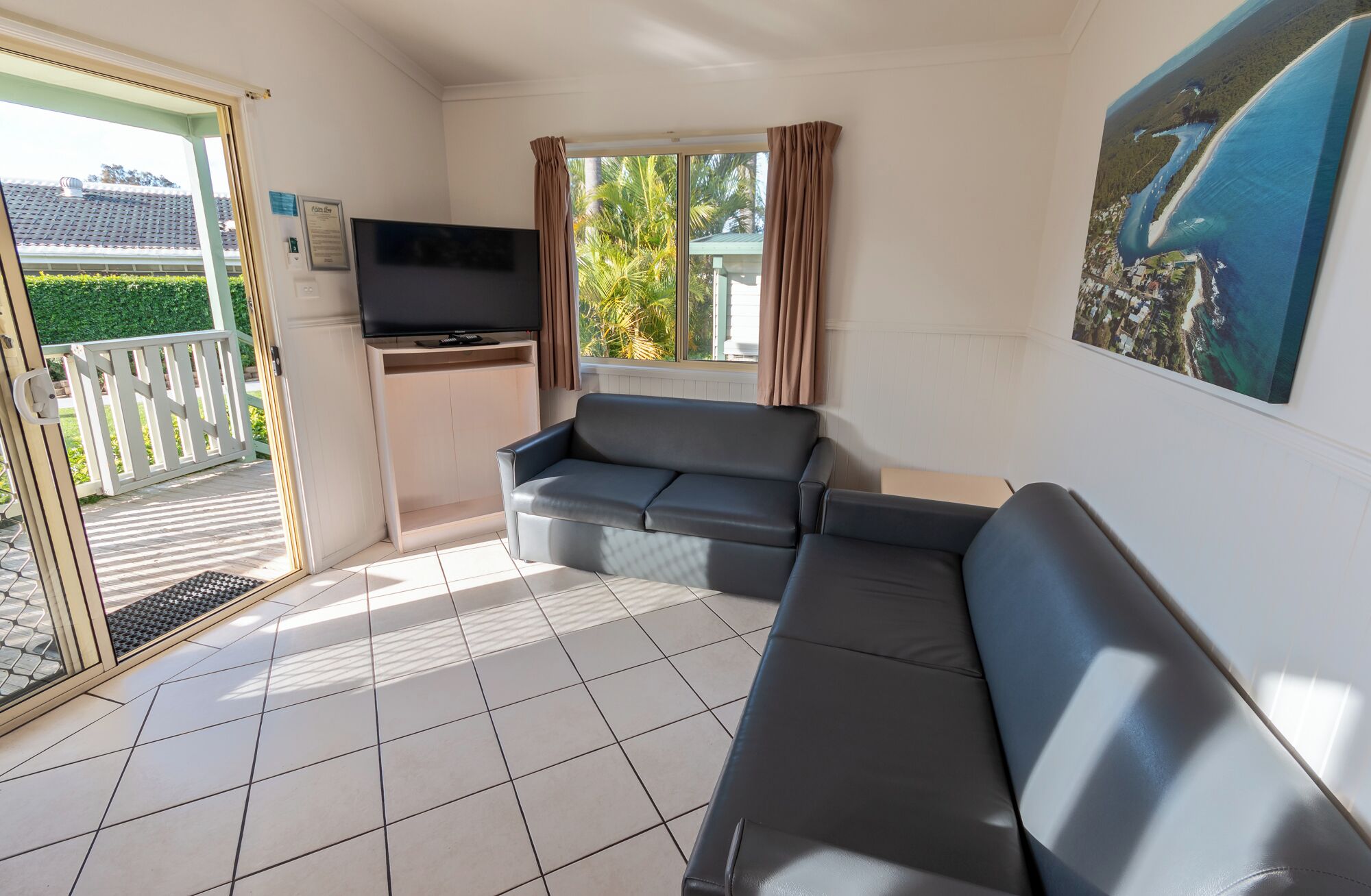 Ein Wohnzimmer mit einer Couch, einem Fernseher und Blick ins Freie.