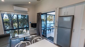 A modern kitchen with a built-in refrigerator, a dining area with a table and chairs, and a large window offering a view of trees and a body of water.