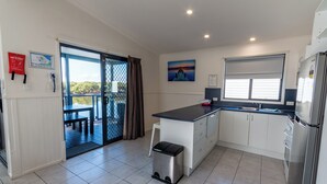 A modern kitchen with a large island, a refrigerator, and a window with blinds.